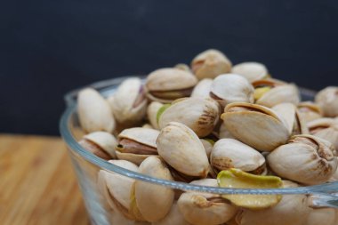 Ahşap bir masaya konmuş cam bir kaseyi taşıran kavrulmuş şam fıstığı, baştan çıkarıcı bir aperatif yaratır.
