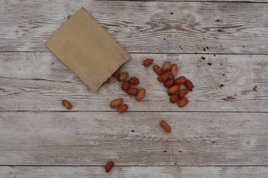 Fıstıklar küçük bir kesekağıdından kırsal bir tahta masaya dökülüp doğal ve davetkar bir sahne yaratıyorlar.