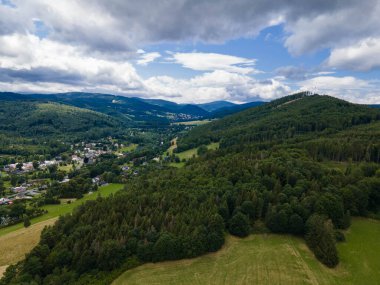 Ormanlı Jeseniky tepeleri ve vadide küçük bir köy. Çek Cumhuriyeti.