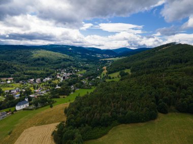 Ormanlı Jeseniky tepeleri ve vadide küçük bir köy. Çek Cumhuriyeti.