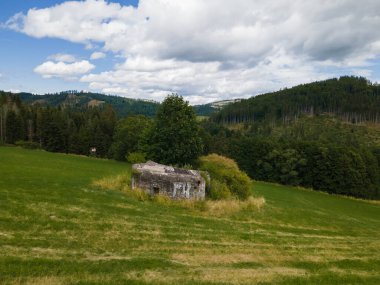 Ormanı, tepeleri ve beton sığınağı olan çayırlar. Çek Cumhuriyeti.