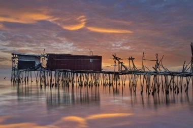 Gün batımında sahilde balıkçı kulübeleri..