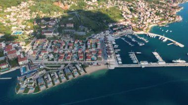 Aerial 4K Drone footage of Portonovi of Montenegro, red rootops and stone buildings with sun light and harbour with boats and new city at background with beautiful blue sea water