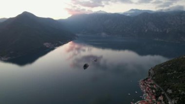Perast 'in 4k hava görüntüsü, Montgro' nun ünlü turistik kasabalarından biri, gün batımında, renkli bulutlar denizi yansıtıyor.