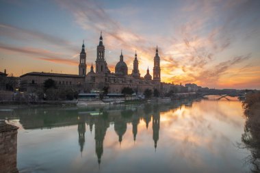 Zaragoza 'nın önemli mimari sembollerinden biri olan del Pilar Bazilikası ve Ebro nehri ve günbatımı renkleri ve bulutlarıyla yansıması.