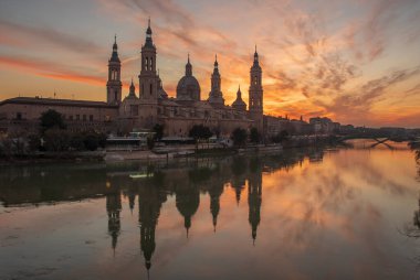 Zaragoza 'nın önemli mimari sembollerinden biri olan del Pilar Bazilikası ve Ebro nehri ve günbatımı renkleri ve bulutlarıyla yansıması.