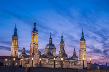 Zaragoza 'nın önemli mimari sembollerinden biri olan del Pilar Bazilikası ve Ebro nehri ve günbatımı renkleri ve bulutlarıyla yansıması.