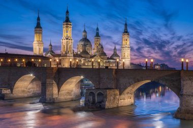Zaragoza 'nın önemli mimari sembollerinden biri olan del Pilar Bazilikası ve Ebro nehri ve günbatımı renkleri ve bulutlarıyla yansıması.