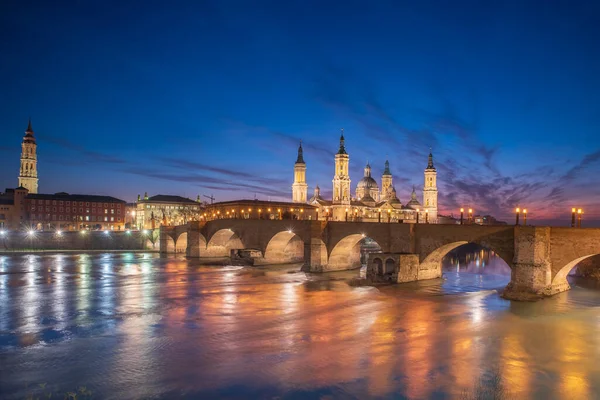 Zaragoza 'nın önemli mimari sembollerinden biri olan del Pilar Bazilikası ve Ebro nehri ve günbatımı renkleri ve bulutlarıyla yansıması.