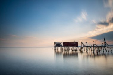 Denize inşa edilmiş ahşap iskeleler ve balık tutmaya yardım etmek, ve günbatımı renkleri ve ışık