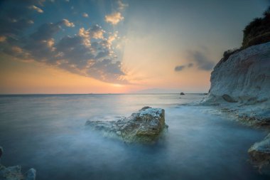 Farklı kaya formları ve gün batımı ışığı olan tekneler.