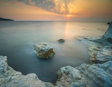 Farklı kaya formları ve gün batımı ışığı olan tekneler.