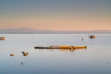 Günbatımında tekneler ve gökyüzü durgun suda yansıyor.