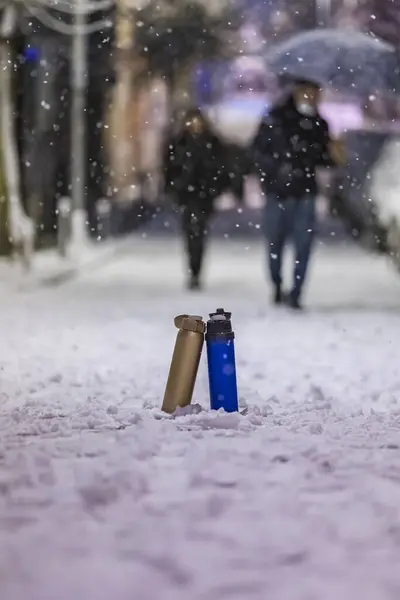 寒い気候の熱い飲み物のアイデアと雪の間に覆われた道の上に立っているカラフルなサーモス — ストック写真