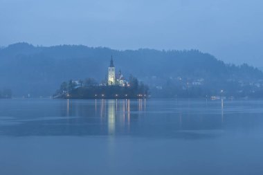 Gölün kanaması Slovenia 'nın günbatımı bulutları ve yansımaları ile aydınlık manzara