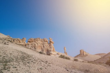 Terkedilmiş doğanın ortasında eşsiz kaya formları. Gün batımı renkleri ve gökyüzünde bulutlar ve güneş ışığı.