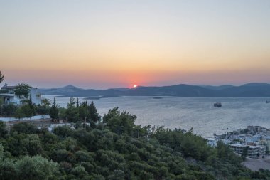 Bursa Golyazi göl kenarındaki yerleşim yeri. Balıkçılık ve tekne turları. Suda ağaçlar.