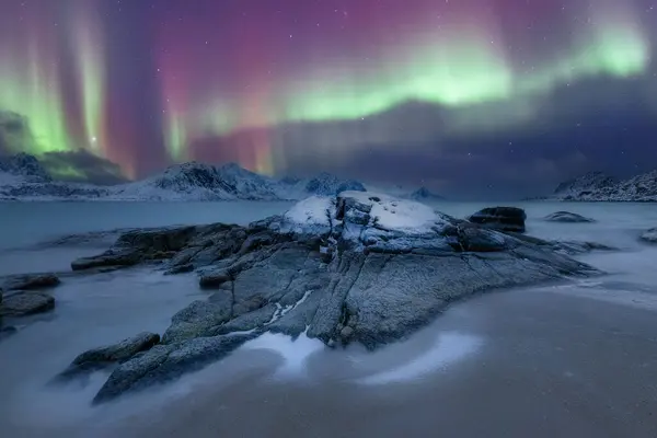 Norveç Lofoten plajı ve gece ışıklı kırmızı evler Kuzey ışıkları aurora borealis
