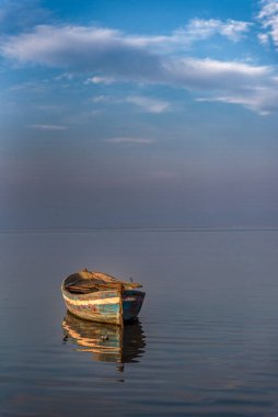 Yansıtıcı su bulutlarında gün batımı renklerinde tekneler bekliyor.