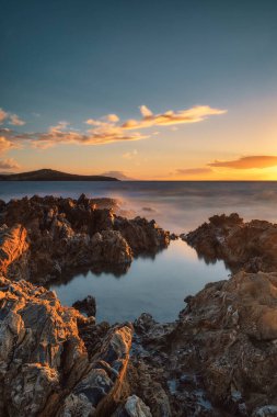 Dalgalar kayalara çarpıyor öğle vakti ve gün batımında deniz göğü