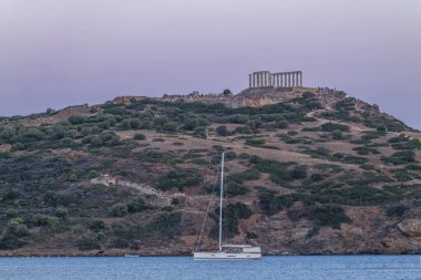 Günbatımında denizde tekneleri olan Yunan ses tapınağı