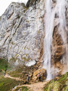 Bir bisikletçi büyük bir şelalenin altından geçer.
