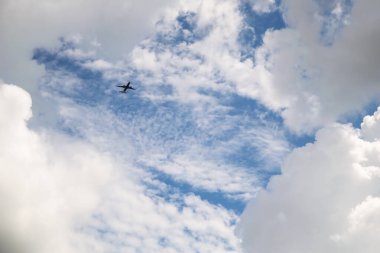 Beyaz ve gri bulutlarda uçan ticari uçak ve Florida 'nın üzerinde mavi bir gökyüzü.