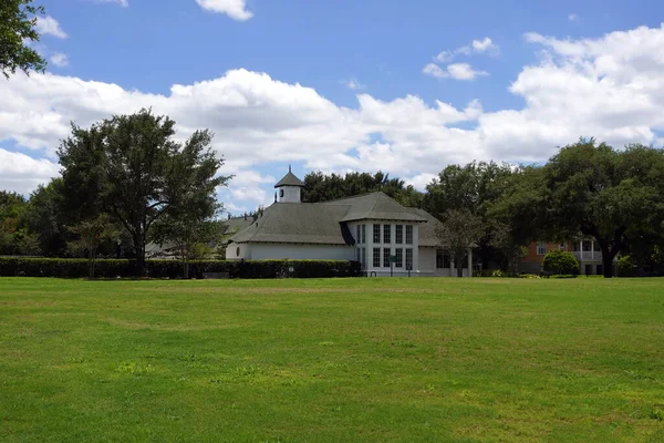 stock image White community clubhouse or recreation facility in a green residential neighborhood park with a large grass field