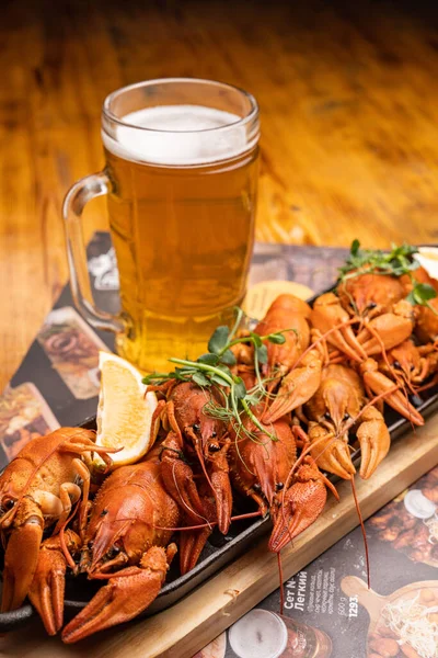 stock image Boiled crayfish with lemon, dill and herbs on a wooden cutting board on blue wooden background. Crayfish dish. Beer party. High quality photo