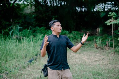 Şok olmuş ve bahçede ne yapacağını şaşırmış bir adam.