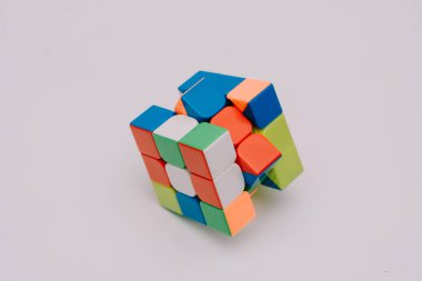 Çözülmemiş bir 3x3 Rubik küp beyaz bir tabanda duruyor