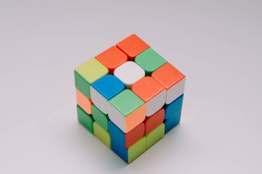 Çözülmemiş bir 3x3 Rubik küp beyaz bir tabanda duruyor