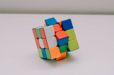 Çözülmemiş bir 3x3 Rubik küp beyaz bir tabanda duruyor