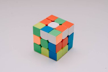 Çözülmemiş bir 3x3 Rubik küp beyaz bir tabanda duruyor