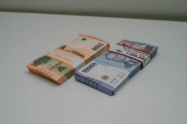 Bankanın logosuyla mühürlenmiş 5 bin rupiah ve 10 bin rupiah tomarı beyaz bir hasırın üzerine yerleştirildi. Bu para bayramda çocuklara dağıtılacak.