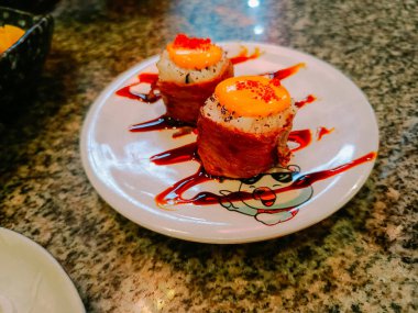 Sığır eti katmanlı suşi ve üzerine iğrenç malzemeler ve balık yumurtası konmuş pirinç.