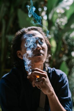 Yetişkin bir adam sigara yakıyor.