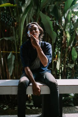 Yetişkin bir adam sigara yakıyor.