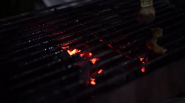 Kömür közleriyle ızgarada kızartılmaya hazır bir tavuk.