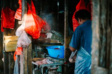 Bekasi, Mei 4 2024. Bir adam pazarda kıyma makinesini ustalıkla çalıştırıyor. Köfte pişirme hizmetlerini istekli müşterilere sunuyor. Geleneksel mutfak işçiliğinin özünü somutlaştırıyor.