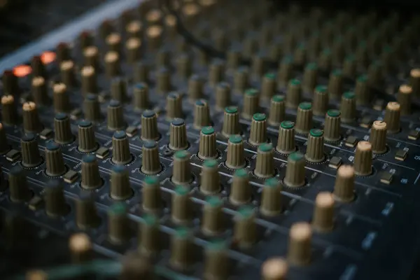 An audio mixer with its knobs and sliders meticulously adjusted, embodying precision and control in the art of sound engineering and music production