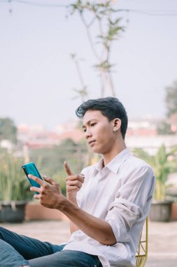 Bir adam akıllı telefonuna şüpheli bir bakışla bakar ve neler olduğunu sorgular.