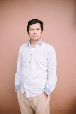 Tarafsız bir yüz ifadesi olan bir adam, basit ama büyüleyici bir görüntüde sakin ve iç gözlem duygusunu somutlaştırıyor.