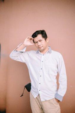 Bir adam saçının sağ tarafını tutuyor, hayal kırıklığı veya derin düşünce sergiliyor..