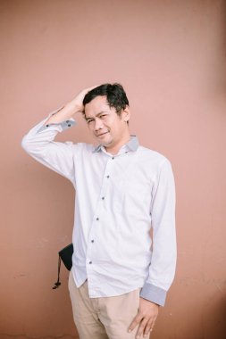 Bir adam saçının sağ tarafını tutuyor, hayal kırıklığı veya derin düşünce sergiliyor..