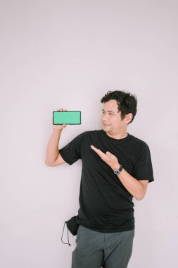 Adamın biri yeşil ekran bir telefonu tutup kameraya doğrultuyor.