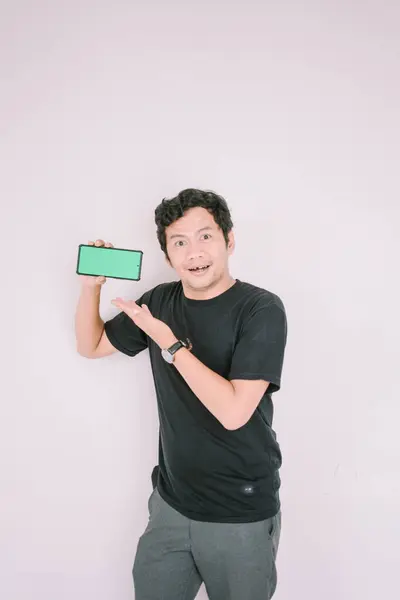 stock image A man holds a greenscreen phone, pointing it towards the camera