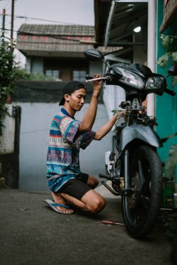 Hasarlı bir motoru kontrol eden bir motosiklet tamircisi.