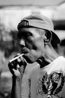 Bogor, 17 Haziran 2024. Orta yaşlı bir adam sigara içiyor, uzaklara bakıyor..