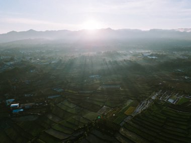 Aydınlık sisli ve parlak bulutlu Gede Dağı 'nın sabah manzarası dingin ve berrak güzelliği yakalıyor.